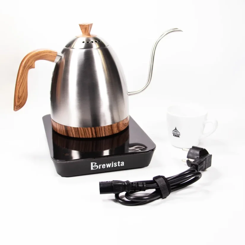 Silver electric kettle with a wooden handle on a black base with a goose neck, on a white background with a cup of coffee, a power cable in the foreground