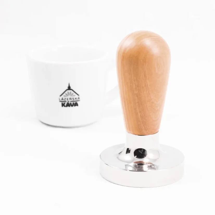 Tamper with an olive wood handle with coffee in the background.