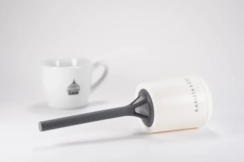 Plastic tea and coffee strainer in white color, with a cup featuring a logo in the background.