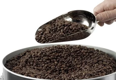 Cuillère en acier inoxydable avec des grains de café sur fond blanc