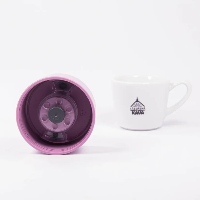 Detail of the inside of a pink thermal bottle lid with a white background and a cup of coffee