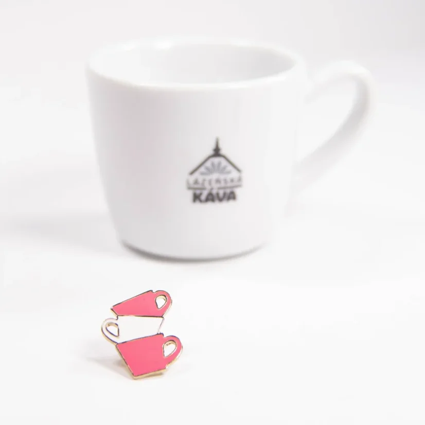 Pink cup pin next to a coffee cup.