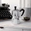Silver Bialetti Moka Express pot for 3 cups on a kitchen counter, a typewriter in the background Silver Bialetti Moka Express pot for 3 cups on a kitchen counter, a typewriter in the background