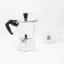 Silver Bialetti Moka Express pot for 2 cups on a white background with a cup of coffee Silver Bialetti Moka Express pot for 2 cups on a white background with a cup of coffee