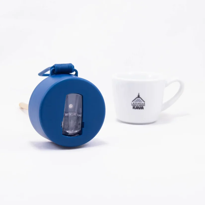 Detail of a ceramic thermos cup with coffee in the background