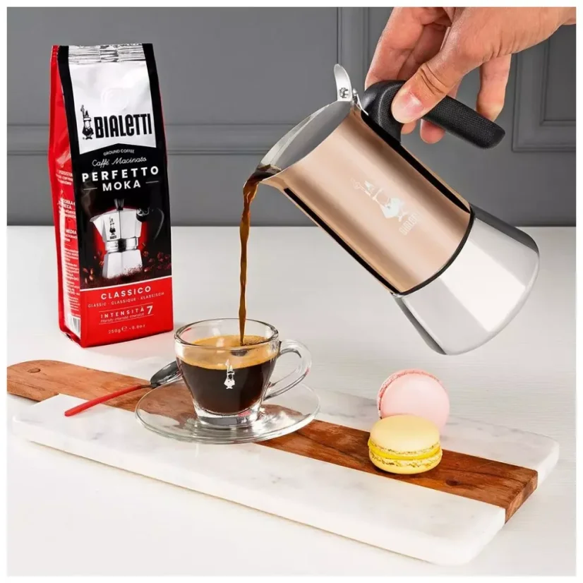 Versamento di caffè preparato dalla caffettiera Bialetti New Venus Copper in una tazza. Accanto c'è un dessert pronto.