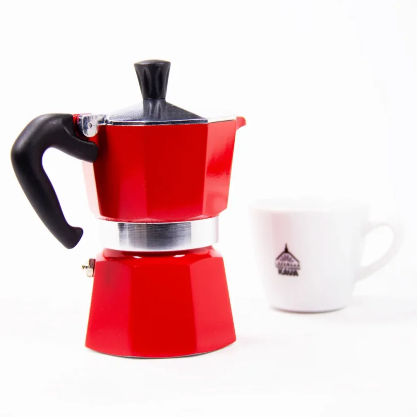 Moka kávéfőző vörös színben a Bialetti márkától egy csésze mellett.