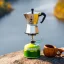 Using a silver Bialetti Moka pot on a gas stove placed on a stone in nature with a wooden mug and forests with a river in the background.