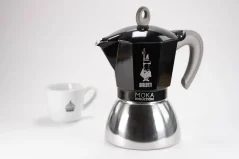 Cafetera Moka de aluminio apta para inducción con el logo del fabricante - empresa italiana Bialetti en composición con una taza con logo.