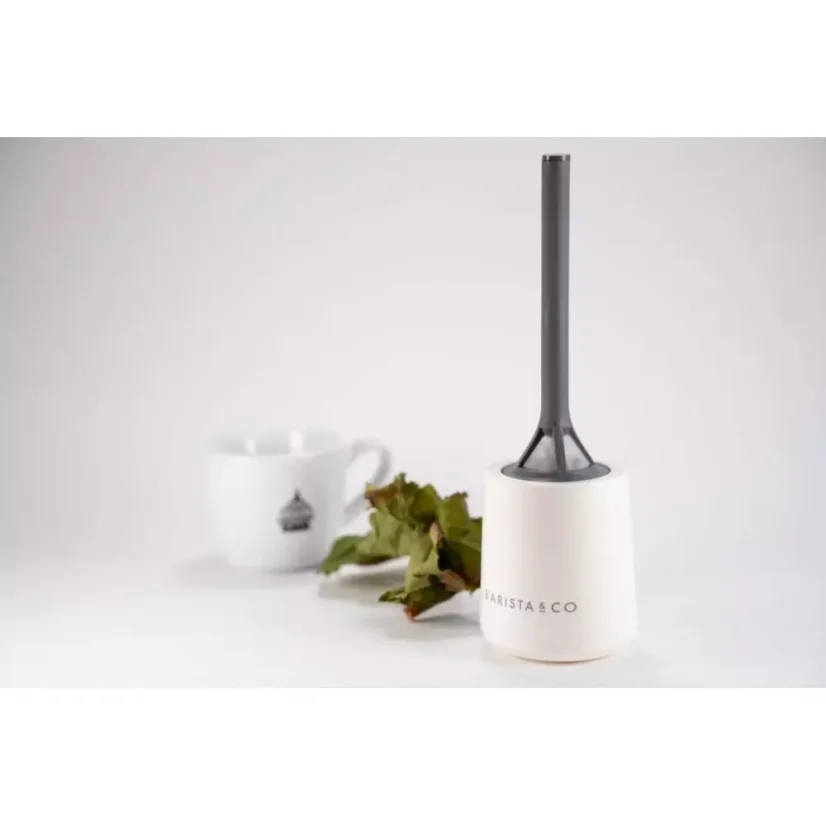 Filtre en plastique blanc avec une structure simple, en arrière-plan une tasse blanche avec une plante.