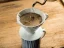 White ceramic Hario V60-01 Dripper in the process of brewing coffee on a rustic background.