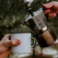Pouring coffee from a Bialetti Moka Express pot into a metal cup.