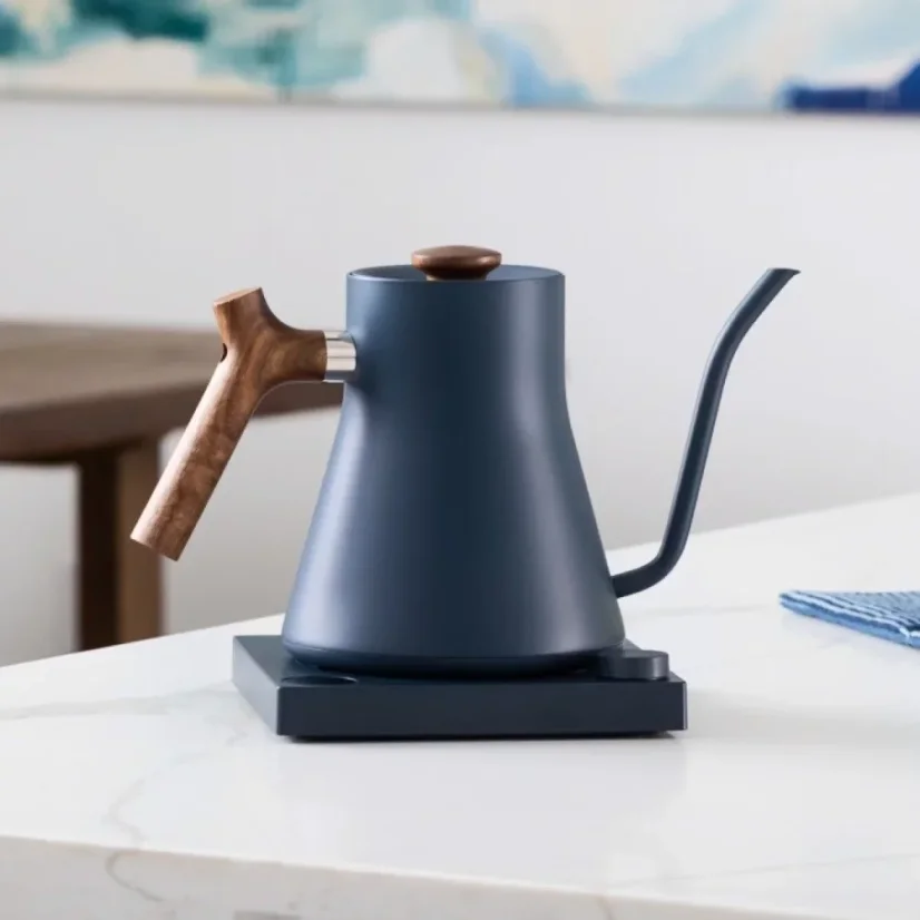 Blue electric Fellow Stagg EKG kettle with a wooden handle and 1200 W power, perfect for pour-over coffee making.