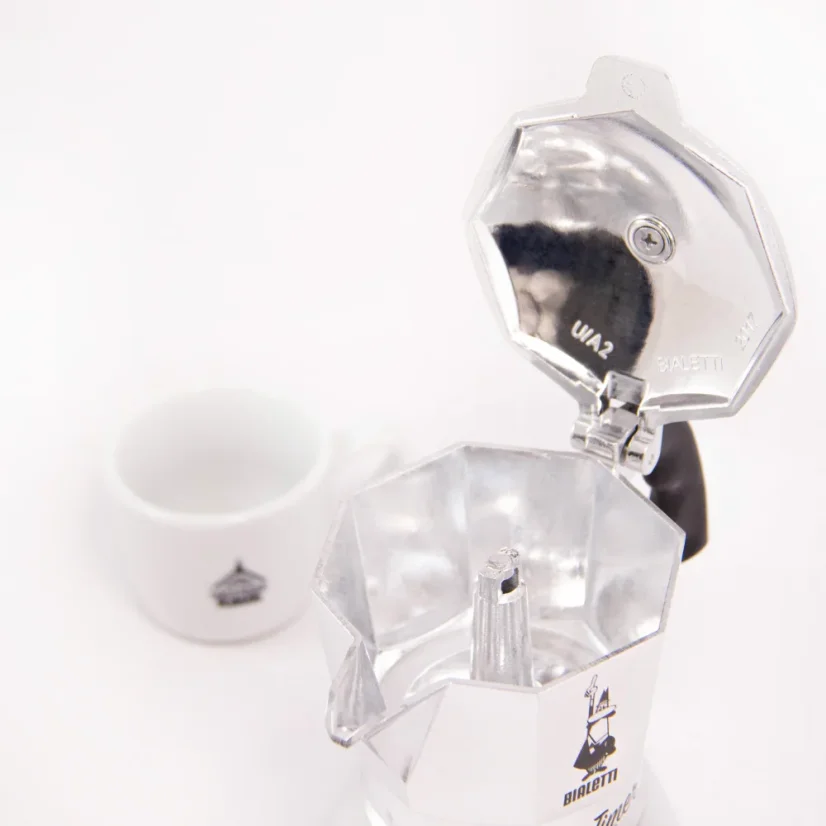Einblick in die silberne Bialetti Moka Timer Kaffeemaschine mit einer weißen Tasse im Hintergrund.