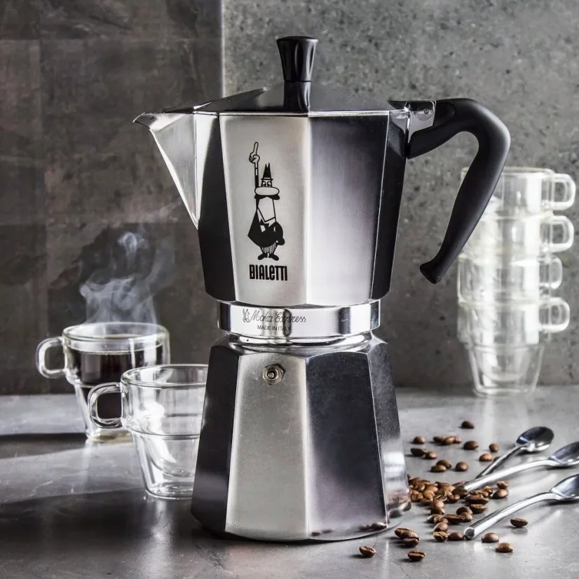 In the foreground, a Bialetti Moka Express coffee maker, with transparent coffee serving cups behind.