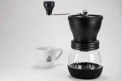 Hario Skerton Plus negro, molinillo de café manual con taza de café.