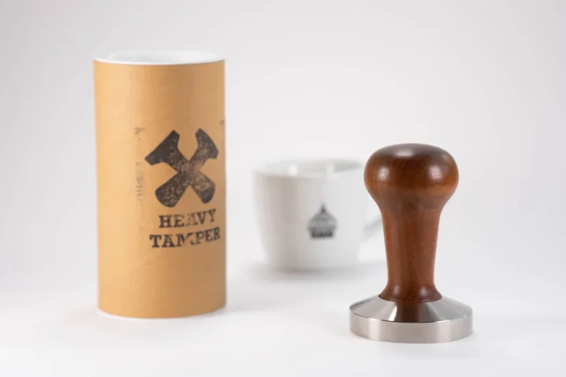 Heavy Temper o priemere 58,4 mm s drevenou rukoväťou na stole spolu s originálnym obalom a porcelánovým šálkom s motívmi