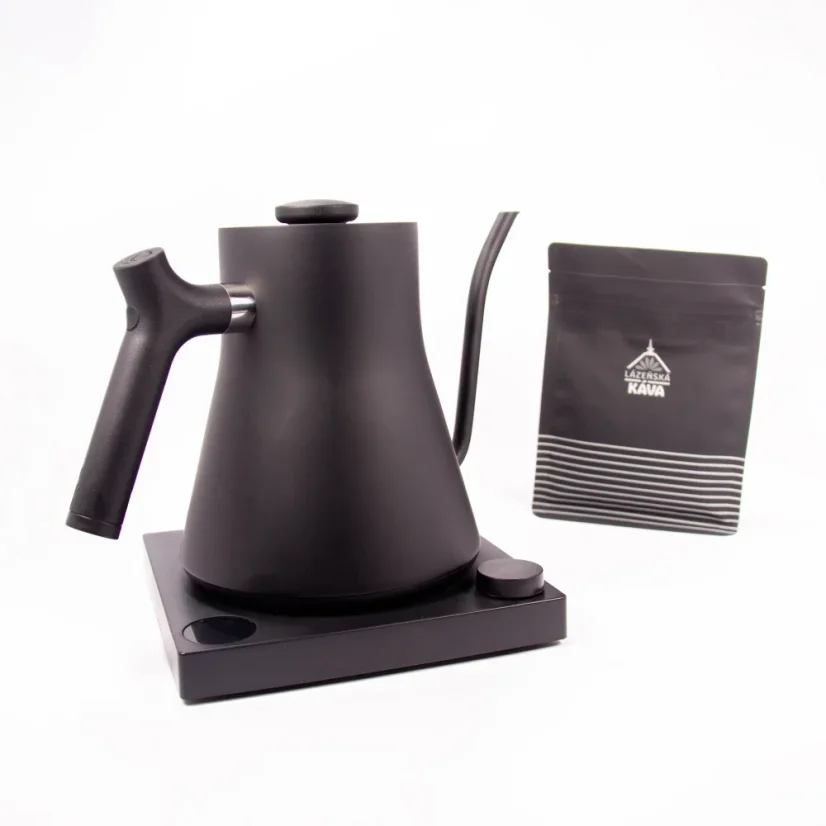 Black electric kettle on a black stand with a white background and a package of coffee, detail on the kettle handle