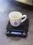 Balance numérique allumée avec un tapis en caoutchouc et une tasse à espresso