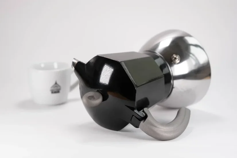 Poignée pratique de la cafetière moka en aluminium de la marque italienne Bialetti, adaptée à l'induction, présentée avec une tasse à café.
