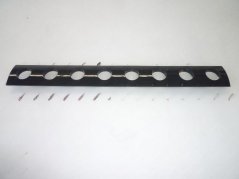 Schwaarz länglech Schutzplack mat enger Rei ovale Lächer fir d'Knäppercher a Schrauwen. Schwaarz länglech Schutzplack mat enger Rei ovale Lächer fir d'Knäppercher a Schrauwen.