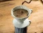 Hario V60-02 keramický biely dripper na rustikálnom pozadí počas prípravy kávy