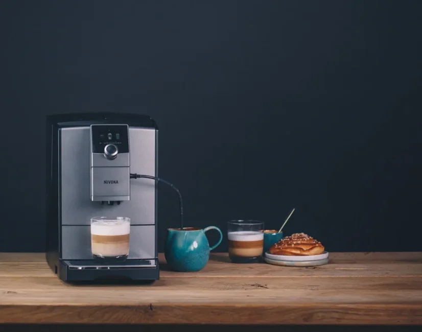 Nivona NICR 795 coffee machine placed on a table with cappuccino and dessert