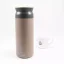 Khaki 500 ml Kino Travel Tumbler thermos with a white cup of coffee in the background