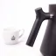Black electric kettle on a white background with a cup of coffee, detail on the kettle's handle