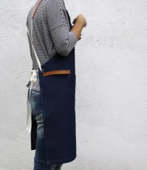Barista apron in blue denim with a model, side view.