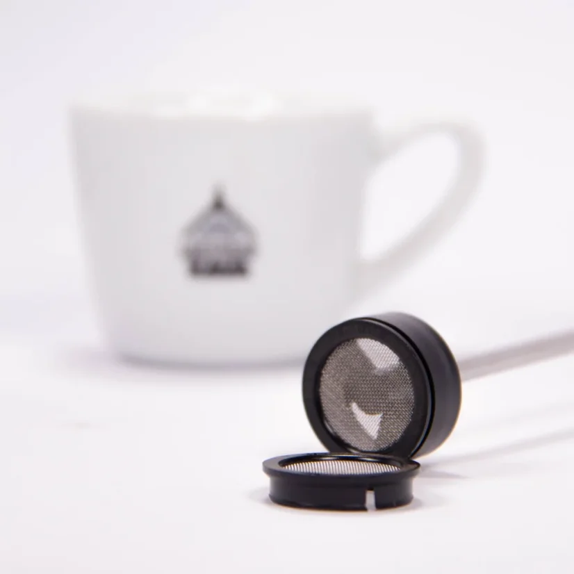 Detail of the frother nozzle with a cup featuring a coffee logo in the background.