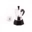 Side view of a Bialetti Moka Elettrika Standard moka pot with a heating source and a white cup of coffee.