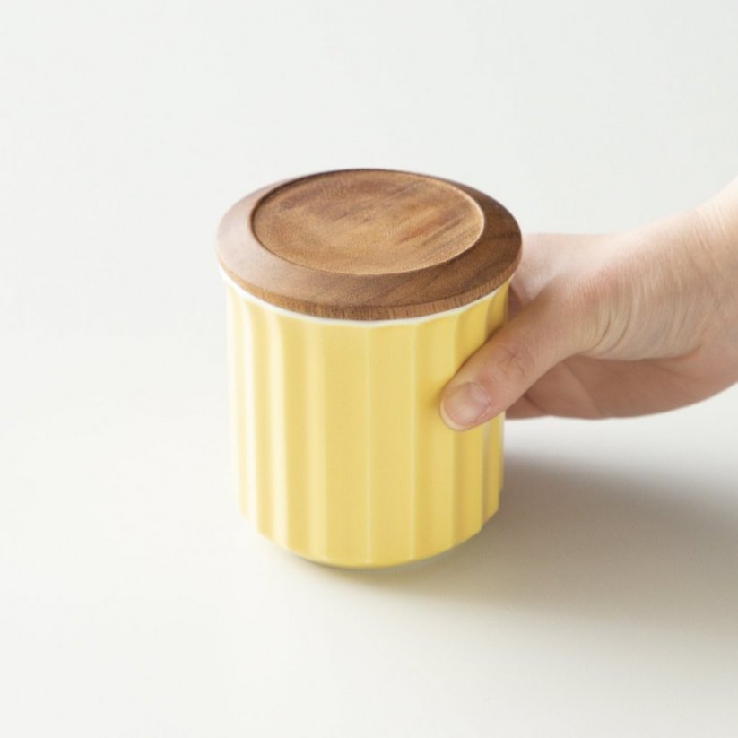 Pot en porcelaine jaune de la marque Origami en main.