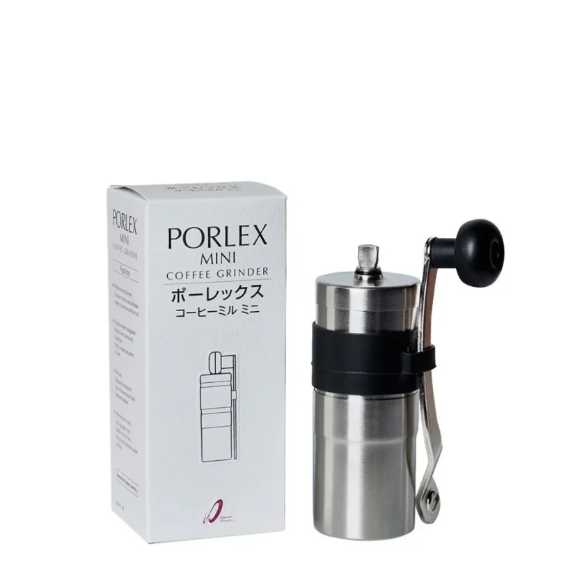 Silver manual coffee grinder next to original packaging on a white background