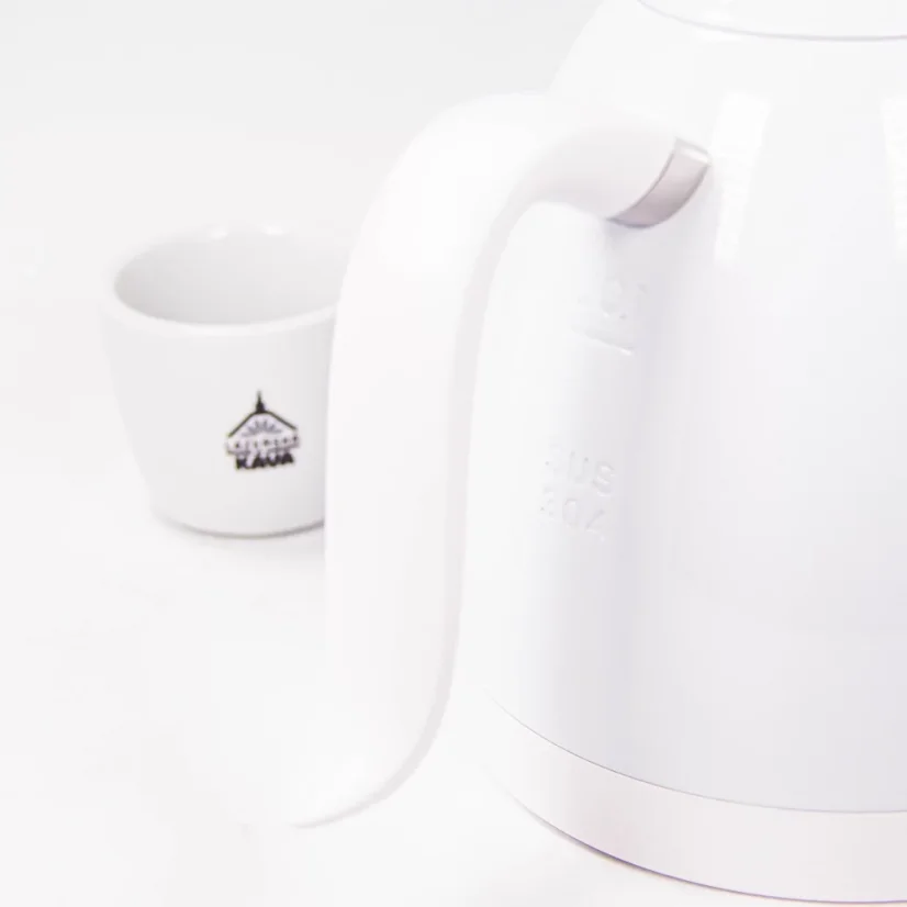 Gros plan sur la poignée pour une manipulation confortable de la bouilloire Brewista avec une tasse arborant un logo en arrière-plan.