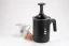 Milk frother in black by Bialetti Tuttocrema with a capacity of 330ml, on a white background along with a cup with a meadow flower.