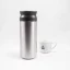 Graue Edelstahl-Thermoflasche Kinto auf weißem Hintergrund mit einer Tasse Kaffee.