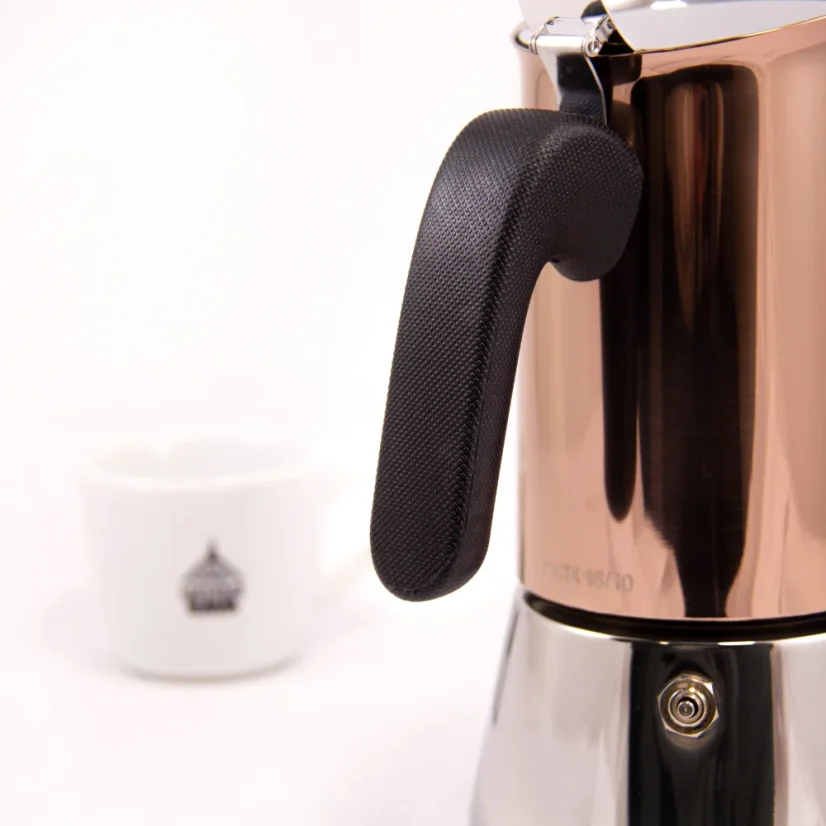 Moka Kanne Bialetti New Venus für 6 Tassen auf weißem Hintergrund mit einer Tasse Kaffee, Detailansicht des schwarzen Griffs der Kanne.
