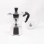 Silver Bialetti Moka Express pot for 2 cups on a white background with a cup of coffee Silver Bialetti Moka Express pot for 2 cups on a white background with a cup of coffee