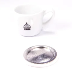 Joint d'étanchéité Bialetti pour cafetière moka à côté d'une tasse à espresso.