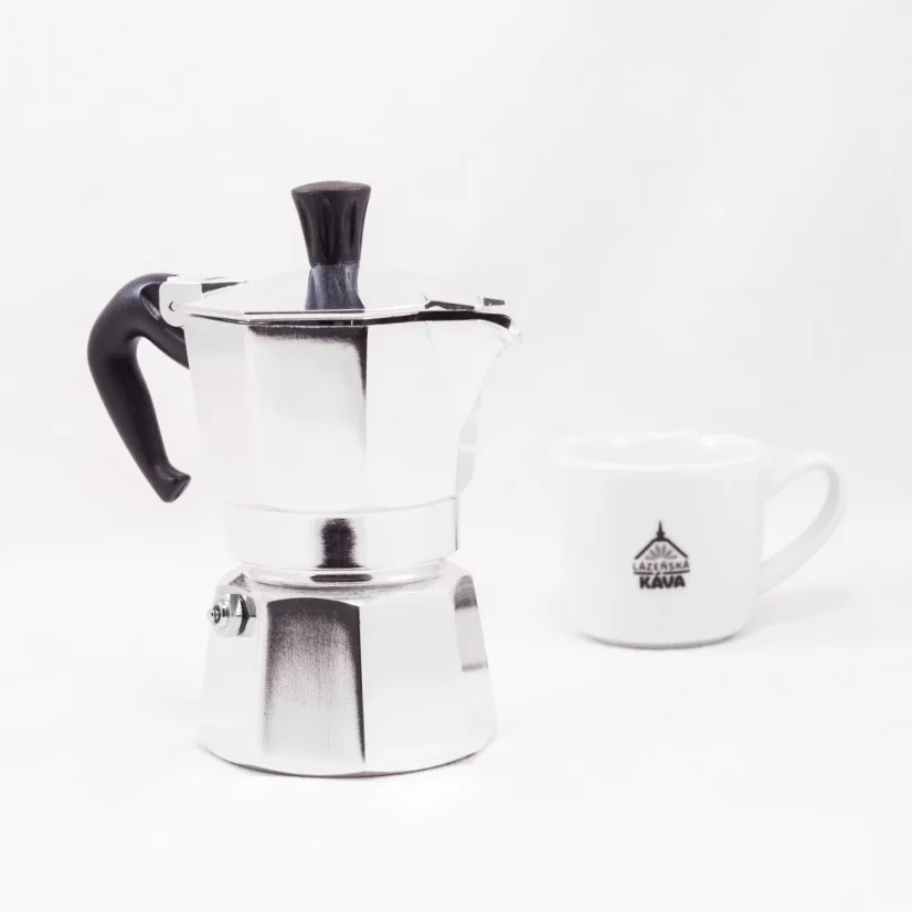 Silver Bialetti Moka Express pot for 2 cups on a white background with a cup of coffee