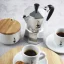 Silver Bialetti moka pot with coffee prepared in cups.