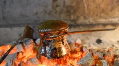 Demonstration of preparing authentic Turkish coffee in a copper cezve over a blazing fire.