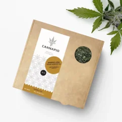 Loose tea with lemon balm in a paper box on a white background with a sprig of lemon balm