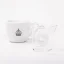 Sklenená odmerka na dvojité espresso pre baristov značky Rhinowares Double Spout Shot Glass vedľa šálky kávy.