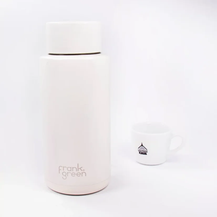 Ceramic thermos from the front with coffee in the background