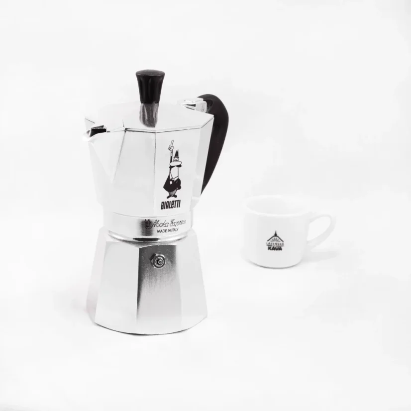 Mokka-Kanne der italienischen Marke mit Bialetti Moka Express Logo im Hintergrund und einer Tasse im Vordergrund.