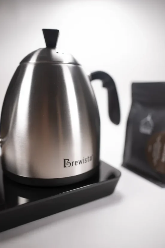 Brewista Smart Pour, bouilloire électrique argentée avec un paquet de café en arrière-plan.