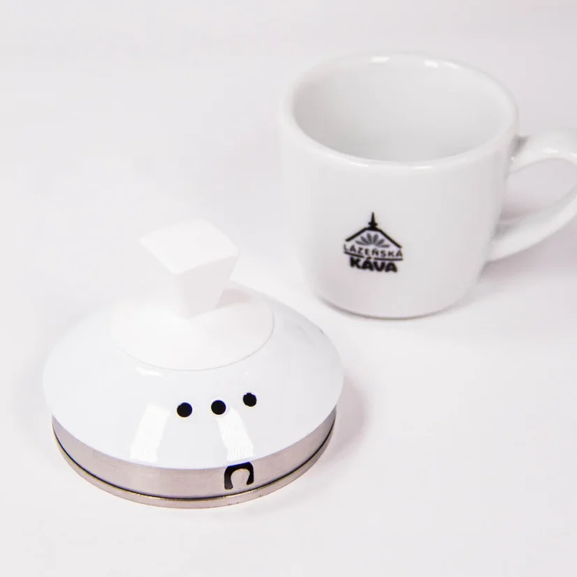 Close-up of the lid of a Brewista electric kettle next to our cup with the logo.