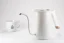 White Timemore Fish Pure Over electric kettle on a white background alongside a cup with decorative patterns.